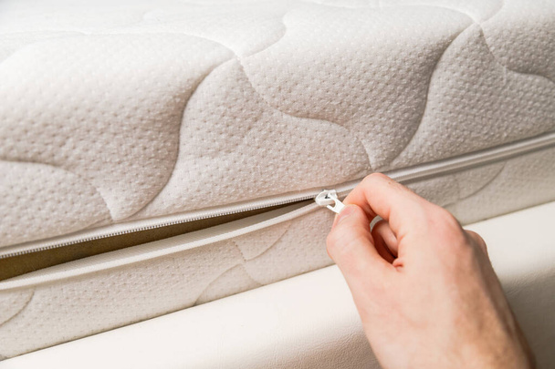 Hand opening cover of new mattress with zipper. Changing and washing cover. Front view. Close up. - Photo, Image