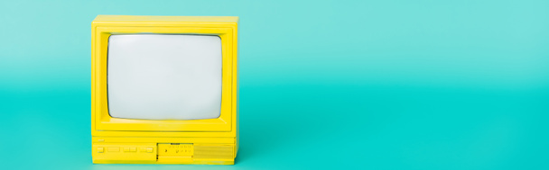 bright yellow retro tv set on turquoise background, banner - Foto, afbeelding