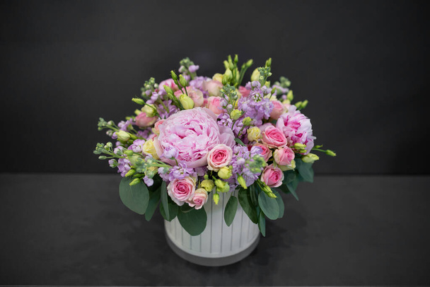 Fresh flowers bouquet with peonies. Assembled in a hat box. Photo on a dark background - Foto, Bild