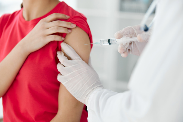 a doctor injects a vaccine into the shoulder of a woman patient close-up - Fotó, kép