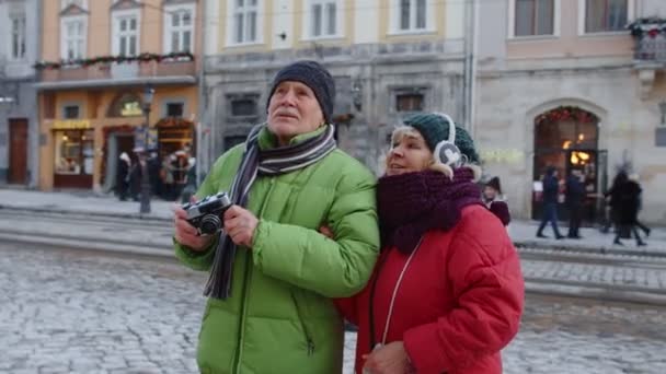 Abuelo tomando fotos con la abuela en la cámara retro en invierno ciudad nevada Lviv Ucrania - Imágenes, Vídeo