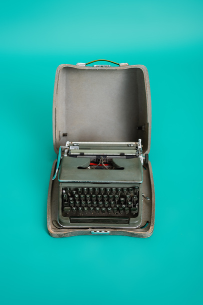 top view of vintage type machine in open case on turquoise background - Foto, Imagem