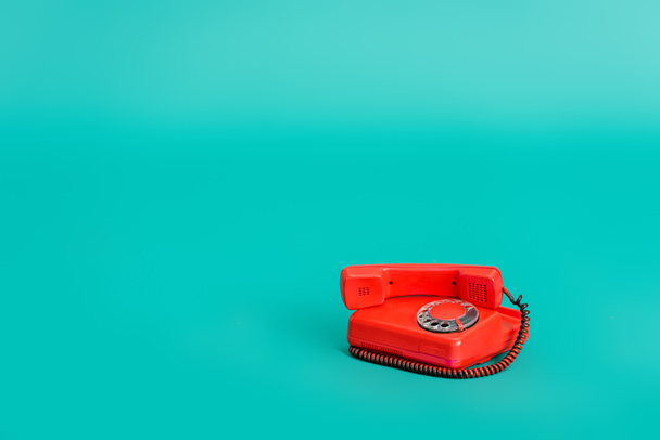 bright red vintage telephone on turquoise background with copy space - Photo, Image