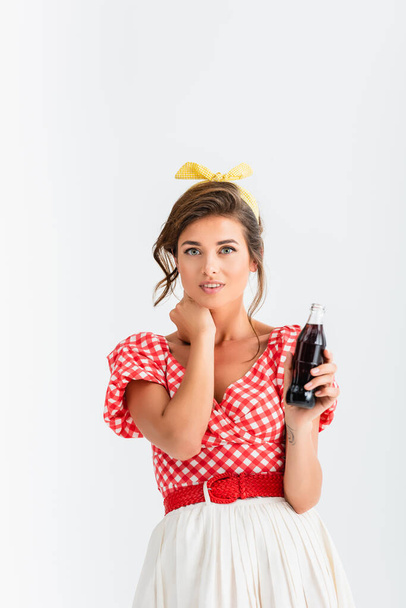 smiling pin up woman with bottle of soda smiling at camera isolated on white - Foto, afbeelding
