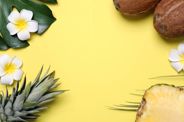 Flat lay composition with pineapples and coconuts on yellow background, space for text - Fotoğraf, Görsel