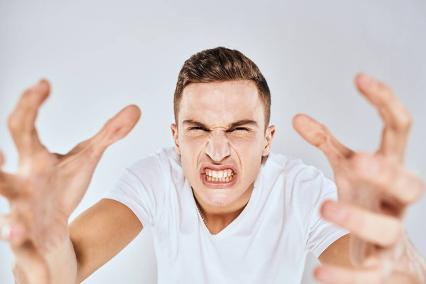 Емоційний чоловік жести своїми руками незадоволення білою футболкою світлого фону
 - Фото, зображення