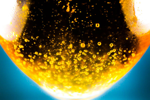 Vloeibare goudgele benzine belletjes achtergrond op bier of champagne glas. Sluit af, macro shot. Zachte focusfoto. - Foto, afbeelding