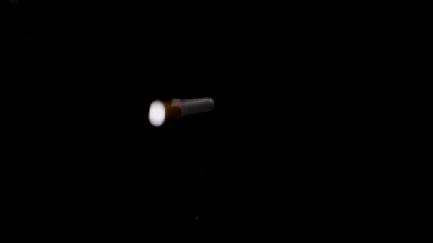 Cigarrillo solo cayendo sobre fondo negro reflectante en cámara lenta. - Imágenes, Vídeo