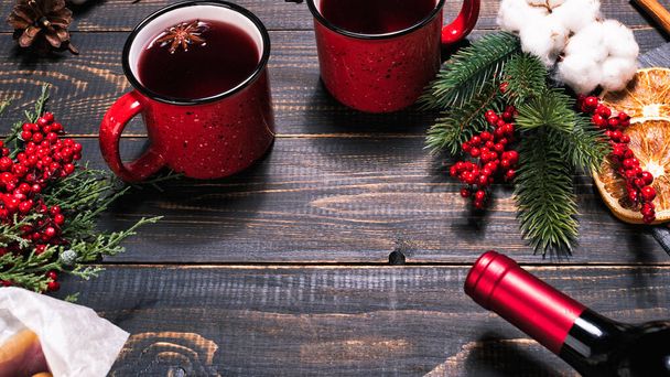 Bottle, mugs and ingridients for mulled wine on wooden dark table - Фото, изображение