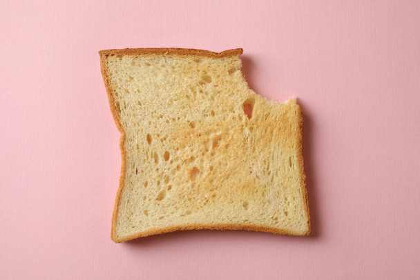 Pan tostado mordido sobre fondo rosa, de cerca - Foto, imagen