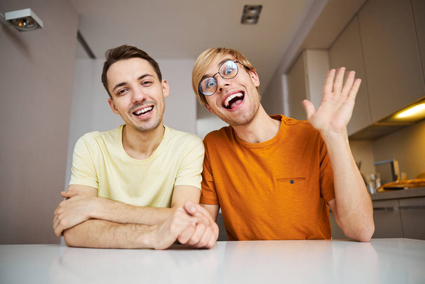 alegre pareja gay sentado en la mesa en casa - Foto, Imagen