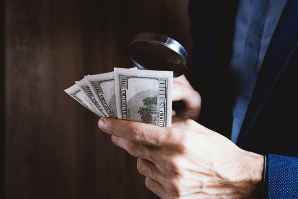 businessman holding a magnifying glass and money - Valokuva, kuva