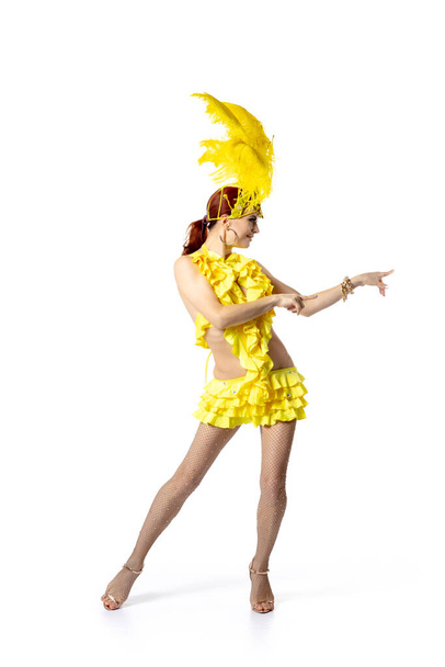Beautiful young woman in carnival, stylish masquerade costume with feathers dancing on white studio background. - Zdjęcie, obraz