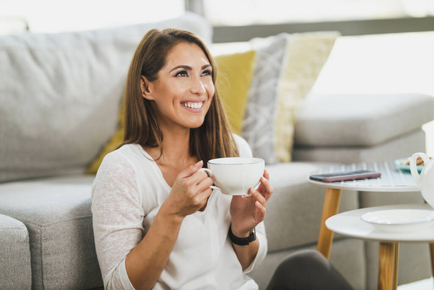 Uma jovem atraente gosta de beber chá em sua casa à tarde. - Foto, Imagem