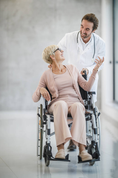 Prise de vue d'un jeune médecin aidant une patiente âgée en fauteuil roulant. - Photo, image