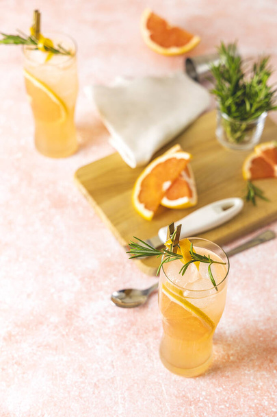 Zwei Highball-Gläser Paloma-Cocktails mit Tequila-frischem Grapefruitsaft kombiniert mit Rosmarin. Umgeben von Zutaten und Barwerkzeugen. Leicht rosa Betonoberfläche. - Foto, Bild