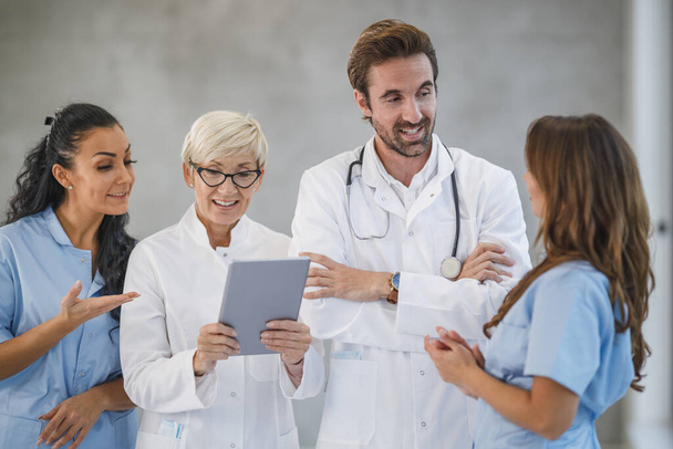Portrait d'une équipe diversifiée de médecins et d'infirmières debout ensemble et utilisant une tablette numérique dans un hôpital. - Photo, image