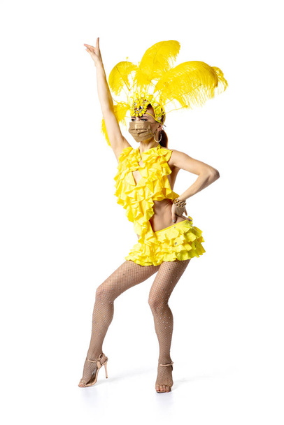 Beautiful young woman in carnival, stylish masquerade costume with feathers dancing on white studio background. - Foto, imagen