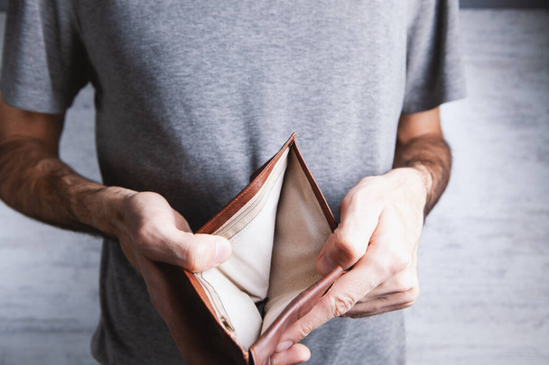 man holds an empty wallet in his hands. - Φωτογραφία, εικόνα