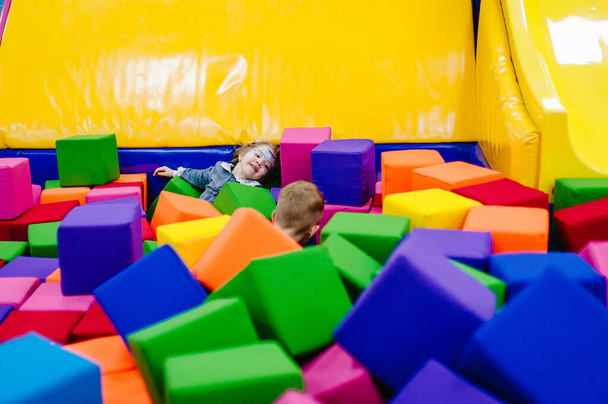 Happy little girl and boy for 2-3 years playing with soft cubes in the dry pool of the game children's room for birthday. time together at the entertainment centre. indoor playground. - Valokuva, kuva