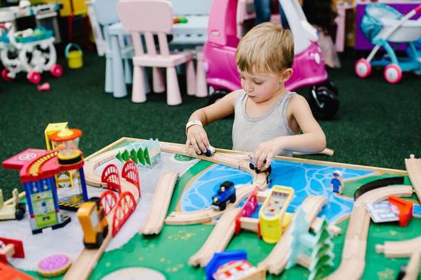 Happy children, baby little boy child playing with wooden car set. Wooden toys cars on road with bridge. The baby in a children's playroom on a birthday party. Time together at entertainment centre. - Φωτογραφία, εικόνα
