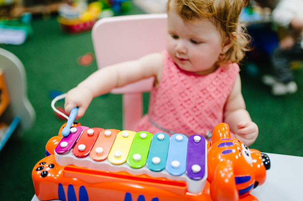 Happy little kid, child, baby girl one year, plays a musical instrument xylophone in children's room for birthday or home. Game center. - Foto, afbeelding