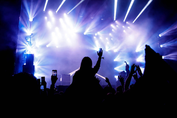 Силуэт многолюдного концерта, музыкальные фанаты на шоу. Поднятые руки и смартфоны. - Фото, изображение