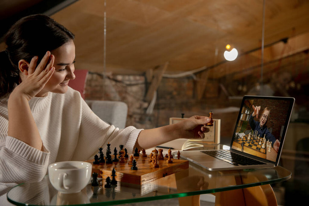 Two people beautiful girl and little boy playing chess online using laptop. - 写真・画像