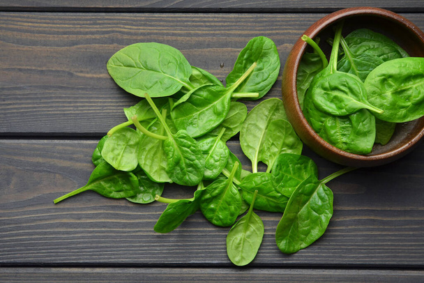 Spinach leaves in wooden bowl on dark wooden table background. Healthy vegan food trend. - Foto, Imagem
