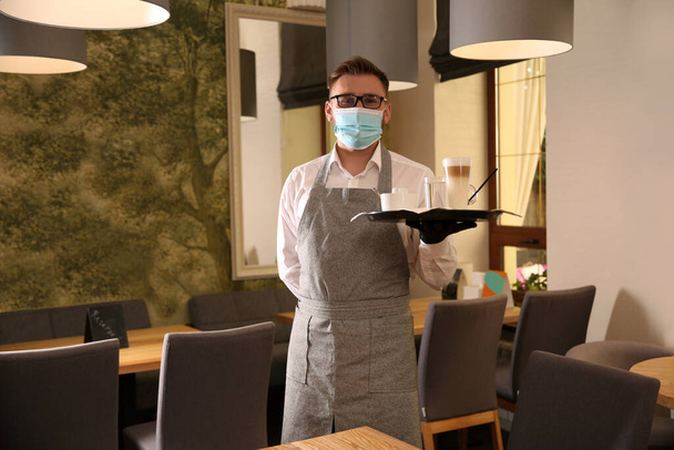 Waiter holding tray with beverages in restaurant. Catering during coronavirus quarantine - Fotó, kép