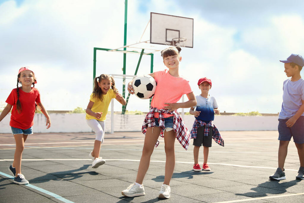 Cute children with soccer ball at sports court on sunny day. Summer camp - Photo, Image