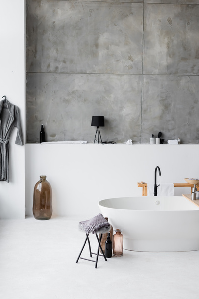 Díszes üvegek közelében fürdőkád a modern fürdőszobában  - Fotó, kép