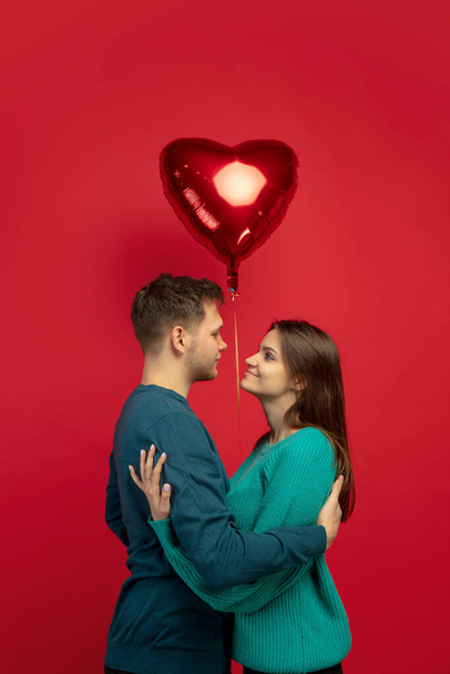 Beautiful couple in love on red studio background. Valentines Day, love and emotions concept - Fotografie, Obrázek