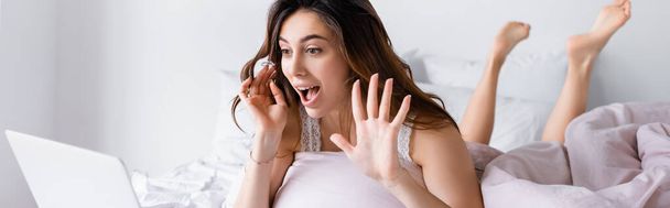 Χαρούμενη γυναίκα που έχει βιντεοκλήση σε φορητό υπολογιστή σε θολή πρόσοψη στην κρεβατοκάμαρα, πανό  - Φωτογραφία, εικόνα