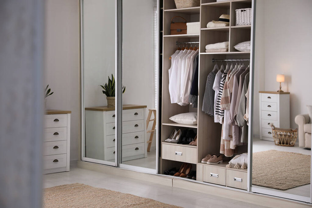 Wardrobe closet with different stylish clothes, shoes and home stuff in room - Фото, зображення