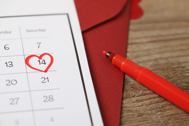 Calendar with marked Valentine's Day and red felt tip pen on wooden table, closeup - Foto, Imagem