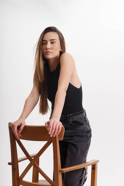 young attractive asian woman with long hair in black clothes sitting on chair - Foto, afbeelding