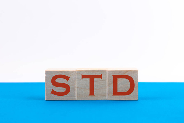 STD inscription on wooden cubes on a blue background - 写真・画像