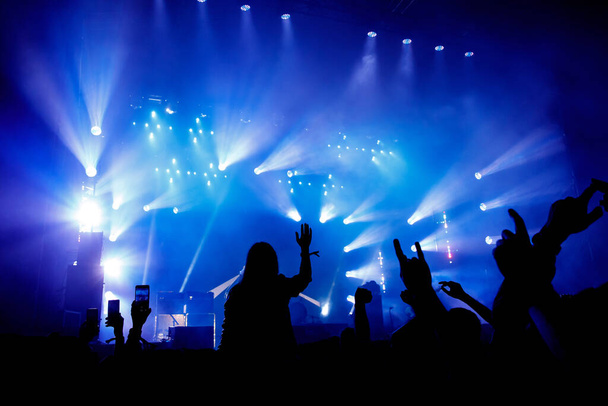 Концерт Силует натовпу, фанати музики на шоу. Підняті руки і смартфони
. - Фото, зображення