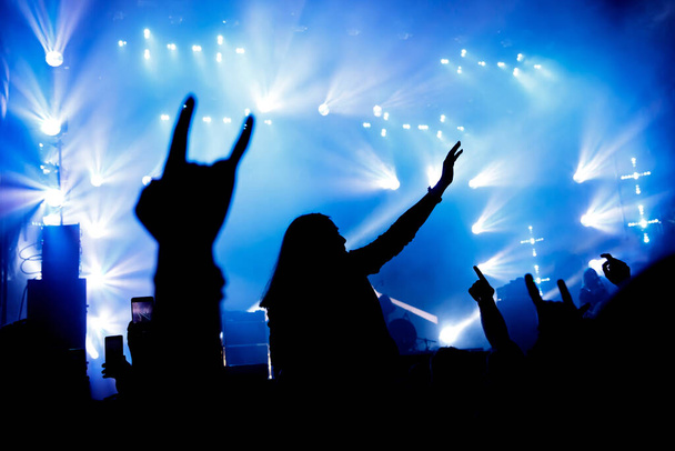 El público en el concierto disfruta. Siluetas de manos elevadas y smartphones - Foto, Imagen