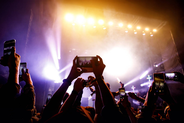 Натовп людей розважається під час перегляду концертного шоу на музичному фестивалі. Підняті руки з мобільними телефонами
 - Фото, зображення
