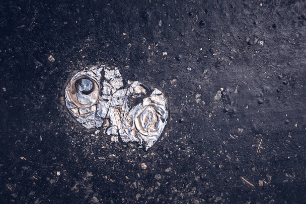 Nahaufnahme einer zertrümmerten Metalldose im Asphalt - Foto, Bild