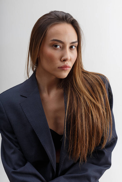 Mavi takım elbiseli genç çekici Asyalı kadın beyaz stüdyo arka planında izole edilmiş. - Fotoğraf, Görsel