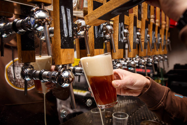 Main de barman versant une bière rouge du robinet. Vie de bar - Photo, image