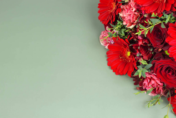 コピースペースと緑の背景に赤い花束の花。バラとガーベラの花の配置. - 写真・画像