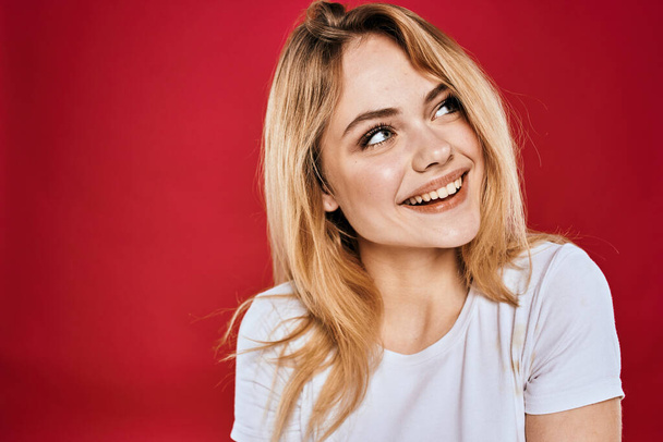 Güzel kadın gülümsüyor beyaz tişört kesilmiş dallar kırmızı arka plan - Fotoğraf, Görsel