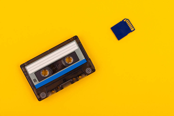 Retro audio cassette from the 80s and SD card on a yellow background. The concept of the past and the present. - Φωτογραφία, εικόνα