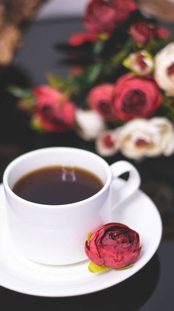 Cup of coffee and flowers. An invitation to a romantic evening. Hearts bokeh, red light effect. Vintage background for postcards. - Zdjęcie, obraz