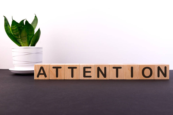 ATTENTION word concept written on wooden cubes on a dark table with a flower and a light background - Foto, imagen