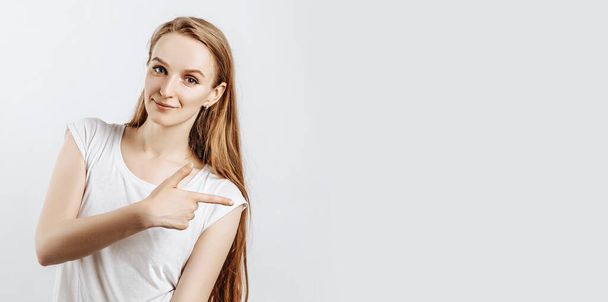 Young beautiful girl smiling and showing finger to the side on gray isolated background - Foto, afbeelding